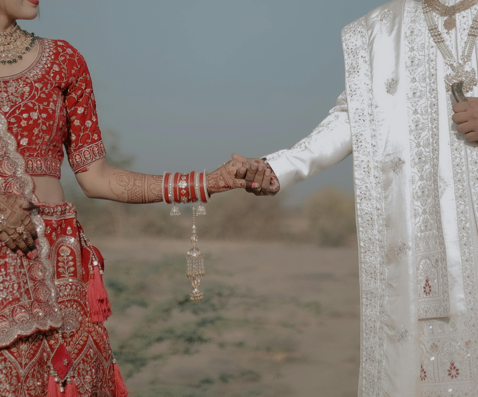 A South Asian bride and groom holding hands at their wedding